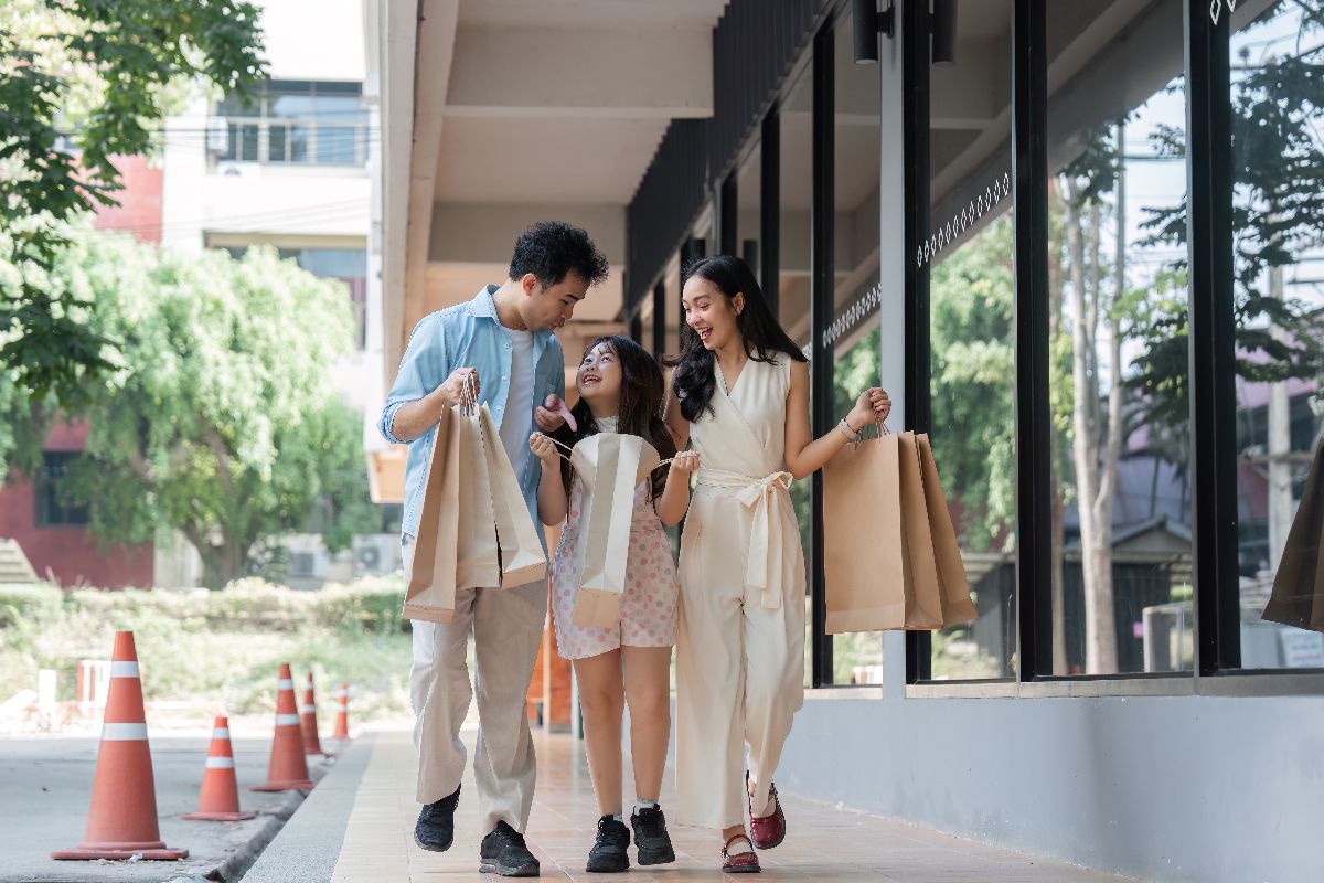 Family walking along a city sidewalk while carrying shopping bags