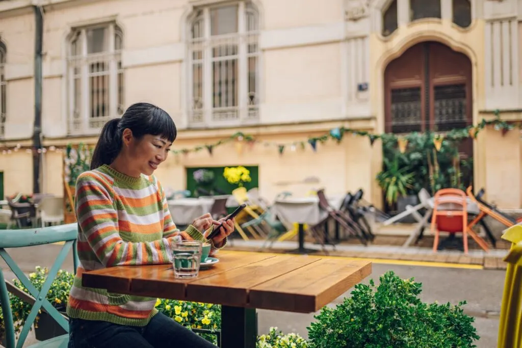 Woman using her phone while seated at an outdoor café table