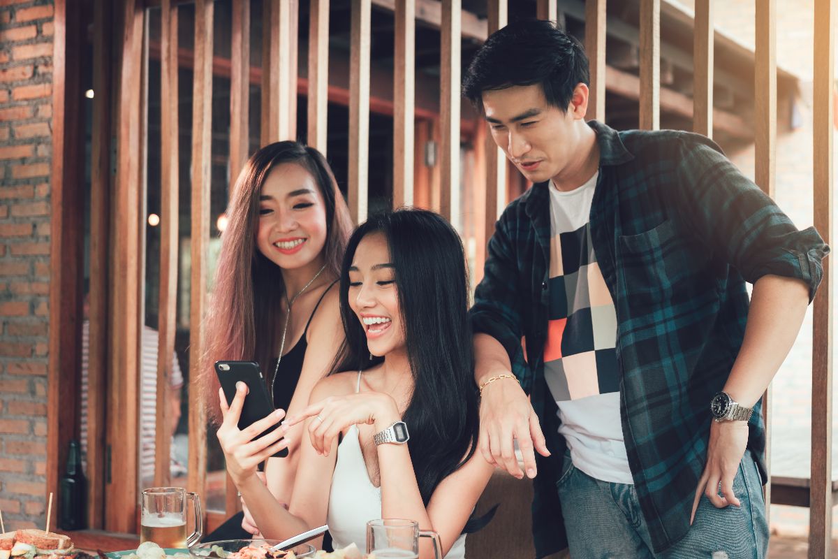 Friends looking at a phone together while dining at a restaurant