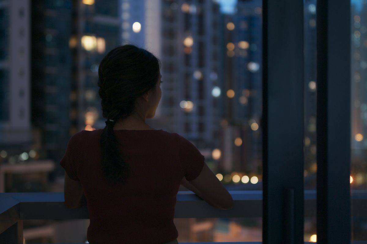 Woman looking out at the city skyline from a balcony at night