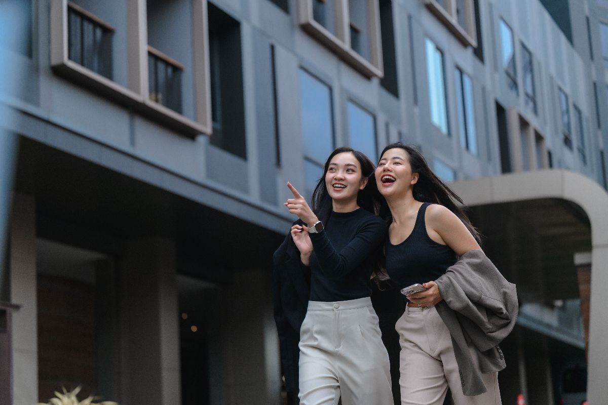 Two women walking happily outside a modern condominium building in Metro Manila