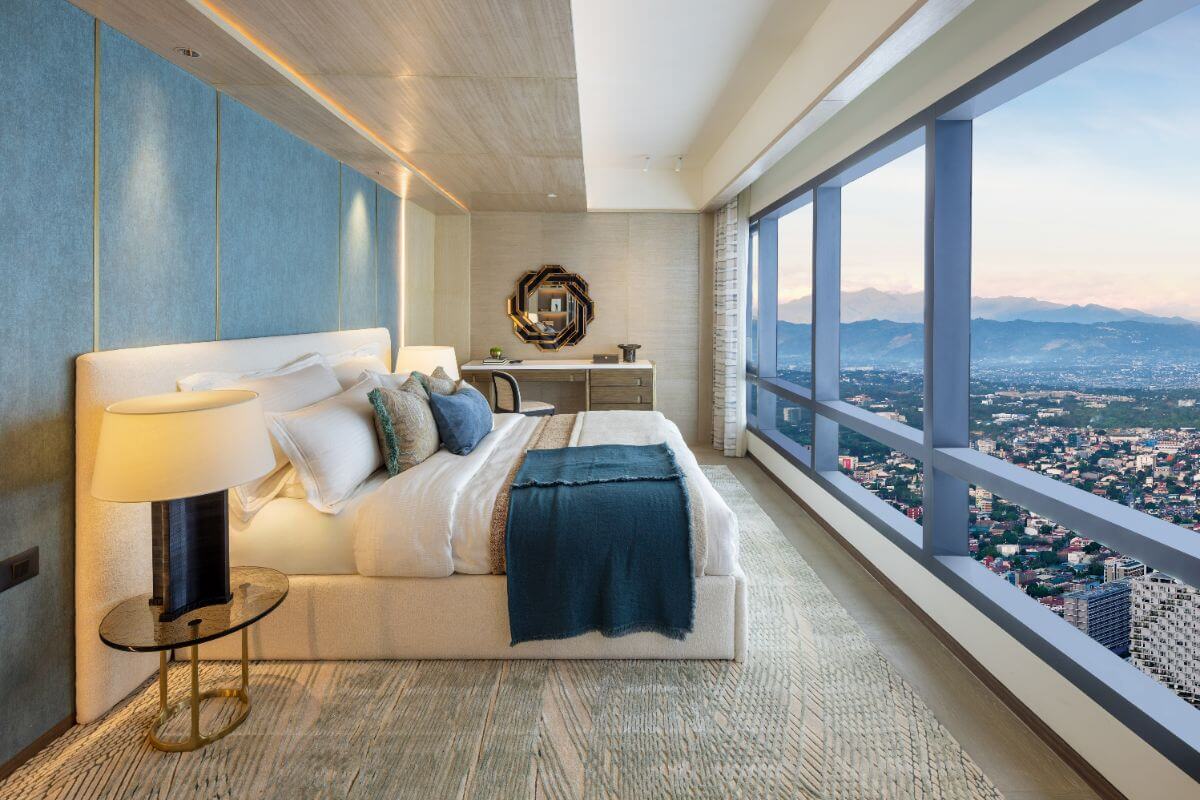 Luxury condo bedroom with floor-to-ceiling windows, city and mountain views, soft lighting, and elegant blue accents