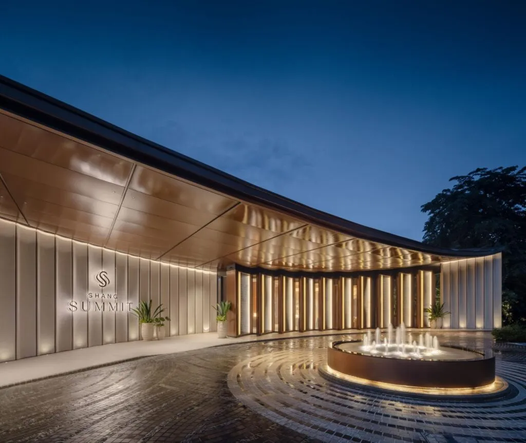 Shang Summit entrance at night with warm lighting, landscaped surroundings, and an illuminated fountain