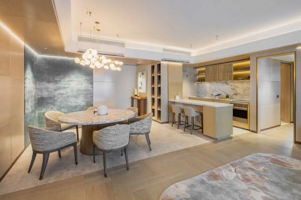 High-end condo dining and kitchen area with marble finishes, warm lighting, textured walls, and elegant modern furniture