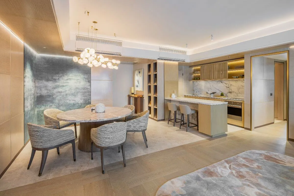 High-end condo dining and kitchen area with marble finishes, warm lighting, textured walls, and elegant modern furniture