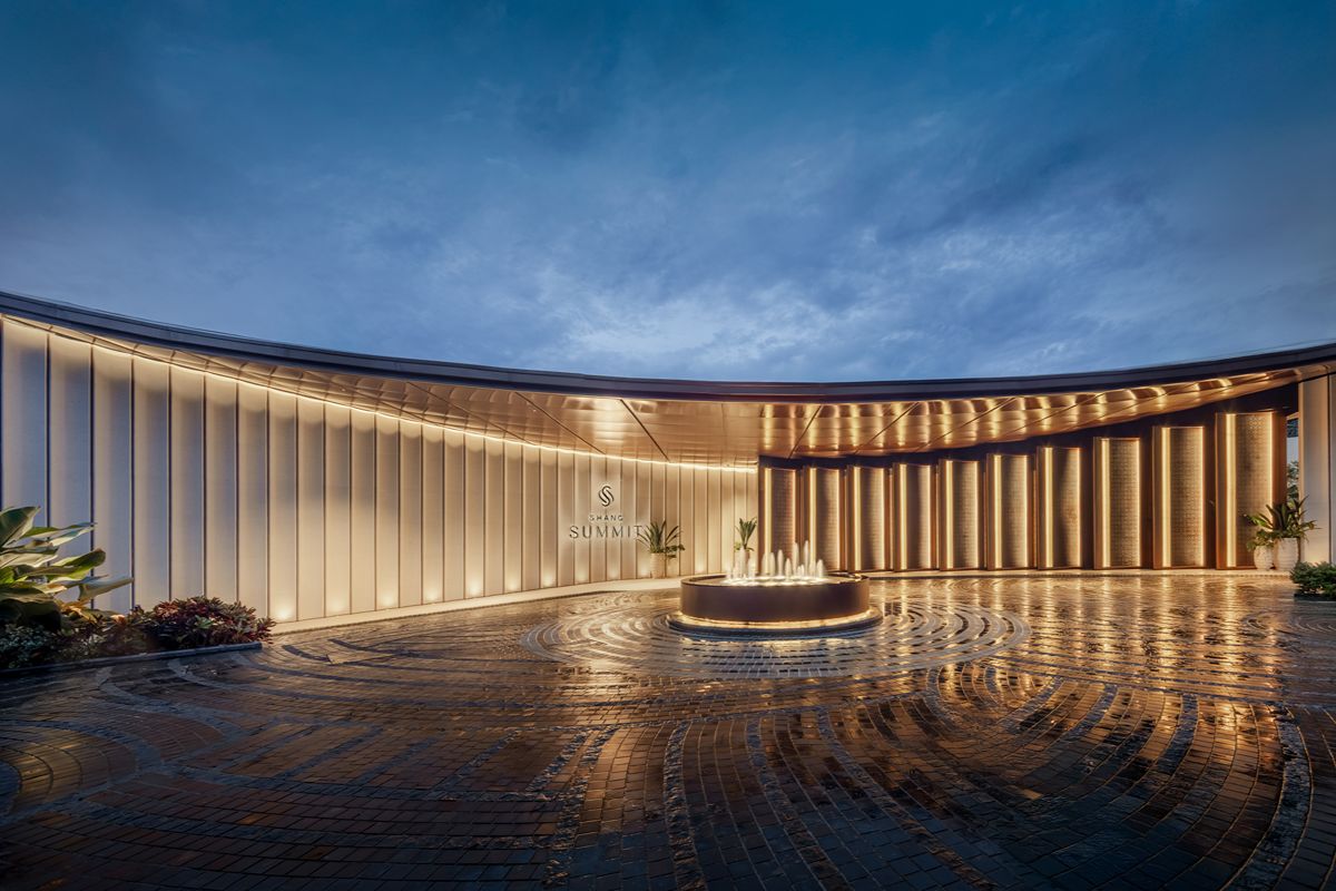 Shang Summit entrance and arrival area with illuminated architectural features and a central fountain at dusk.